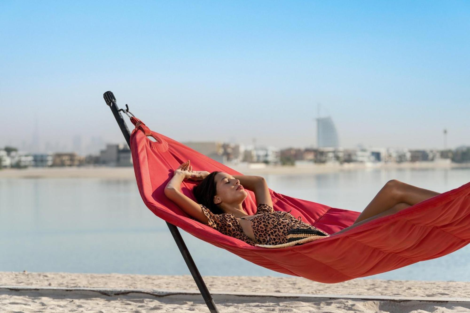 Th8 Palm Dubai Beach Resort, Vignette Collection By Ihg Esterno foto A woman relaxing in a hammock